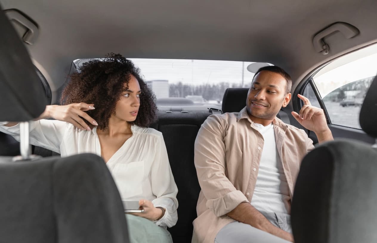 Two passengers relaxing in the back seat of an Xryde, smiling
